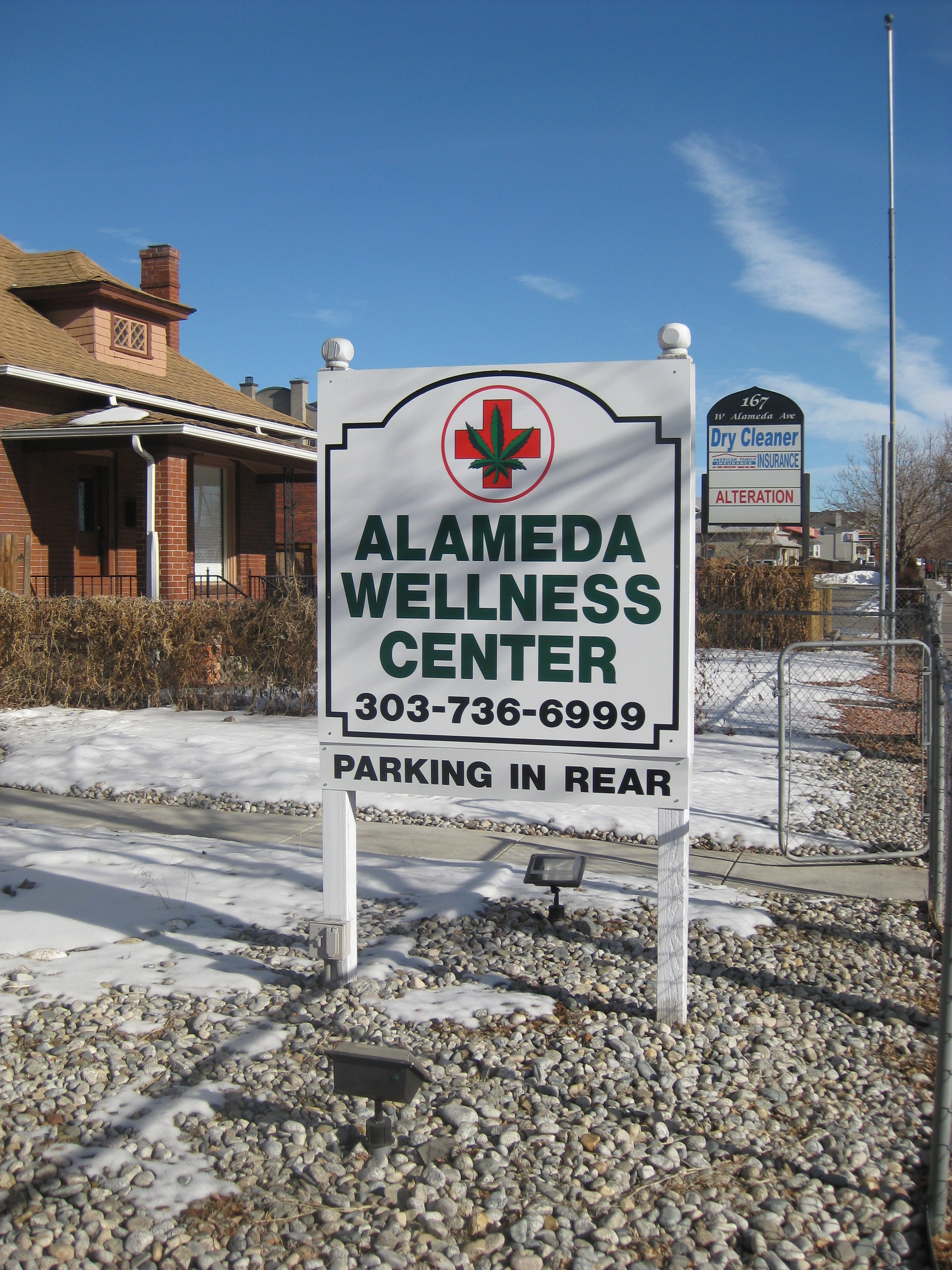 Sign for Alameda Wellness Center (pot leaf in a red cross)  Baker Now